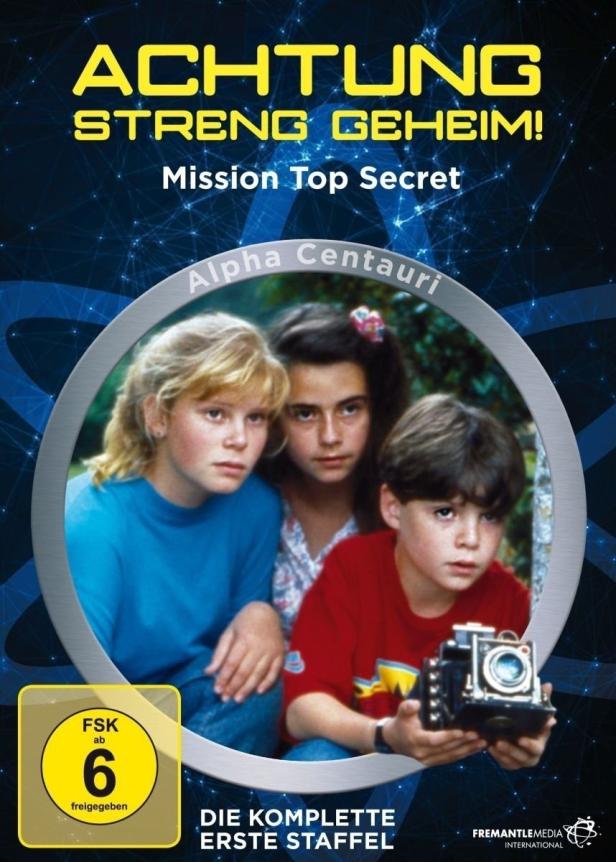Das Cover der ersten Staffel von „Mission Top Secret – Alpha Centauri“ zeigt drei Kinder, eines davon mit einer Kamera.