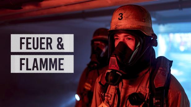 Zwei Feuerwehrleute mit Atemschutzmasken und Helmen im Einsatz.