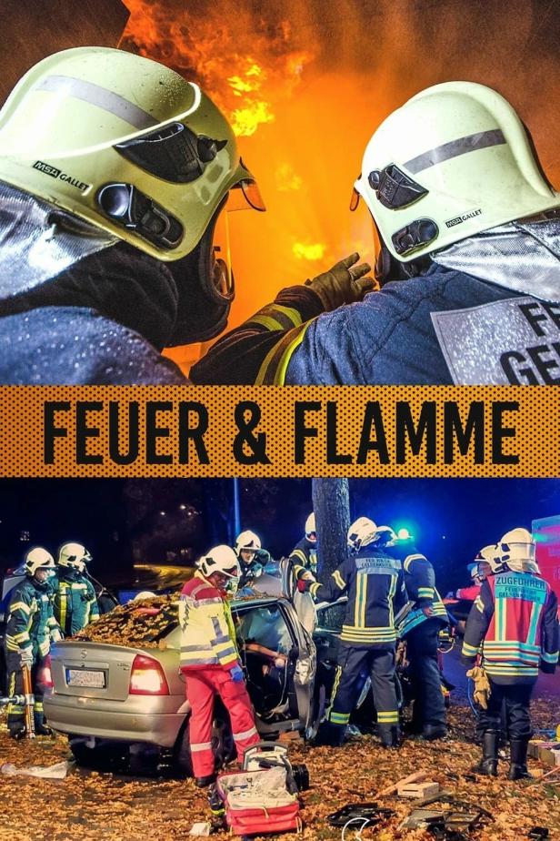 Feuerwehrleute arbeiten an einem Unfallort, während im Hintergrund ein Feuer brennt.