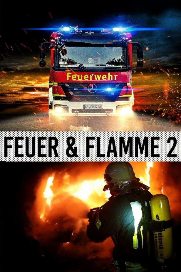 Ein Feuerwehrmann löscht ein Feuer, während ein rotes Feuerwehrfahrzeug mit Blaulicht im Einsatz ist.