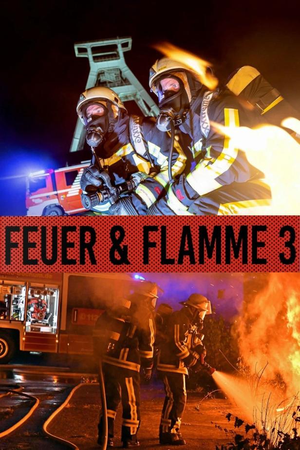 Feuerwehrleute in Schutzkleidung löschen einen Brand vor einem Förderturm.