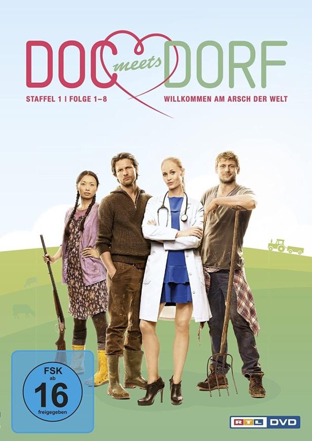 Das DVD-Cover der ersten Staffel von „Doc meets Dorf“ zeigt vier Hauptdarsteller vor ländlicher Kulisse.