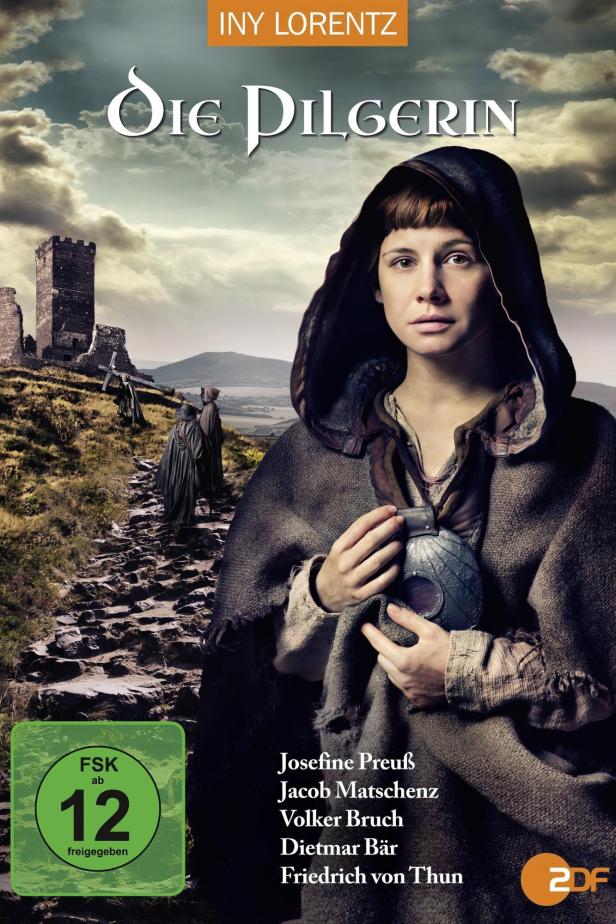 Das Filmplakat für „Die Pilgerin“ zeigt Josefine Preuß in mittelalterlicher Kleidung vor einer Burgruine.