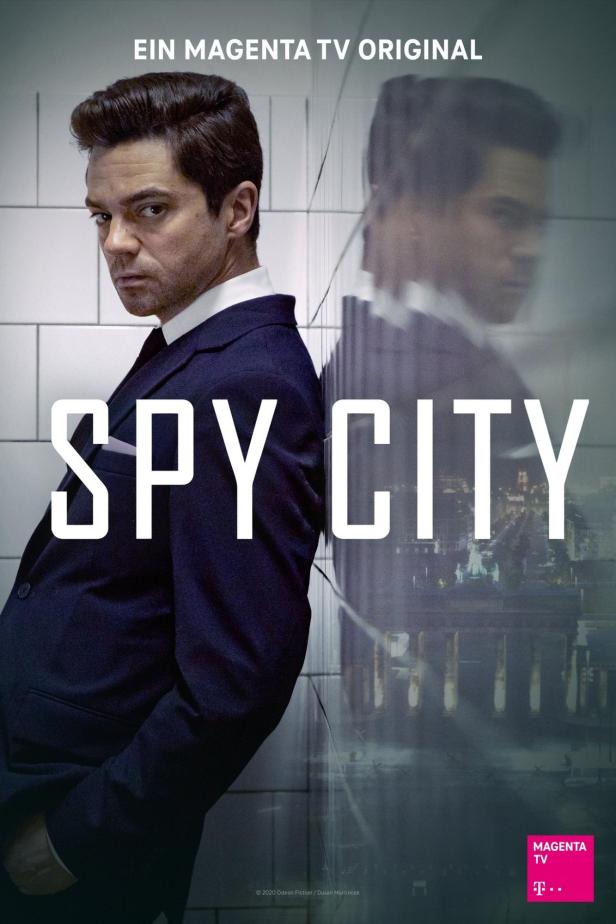 Das Filmplakat für „Spy City“ zeigt einen Mann im Anzug vor einer Berliner Stadtansicht.