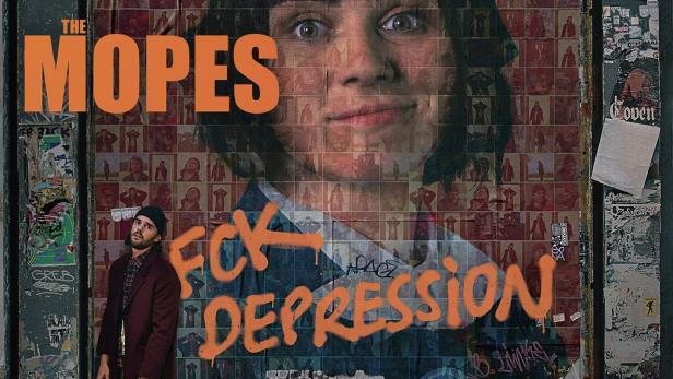 Ein Mann steht vor einer Wand, die mit dem Schriftzug „Fck Depression“ und einem Mosaik aus Porträts bedeckt ist.