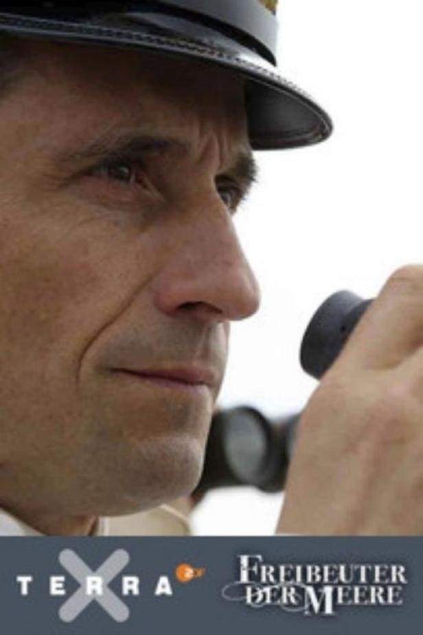 Ein Mann in Marineuniform blickt durch ein Fernglas.