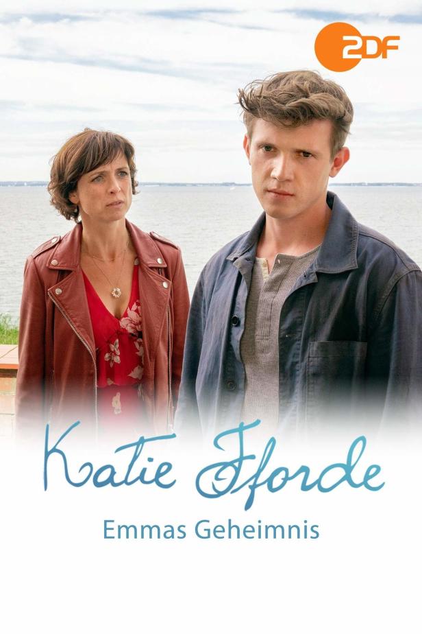Das Filmplakat zu „Katie Fforde: Emmas Geheimnis“ zeigt eine Frau und einen Mann vor einer Küstenlandschaft.