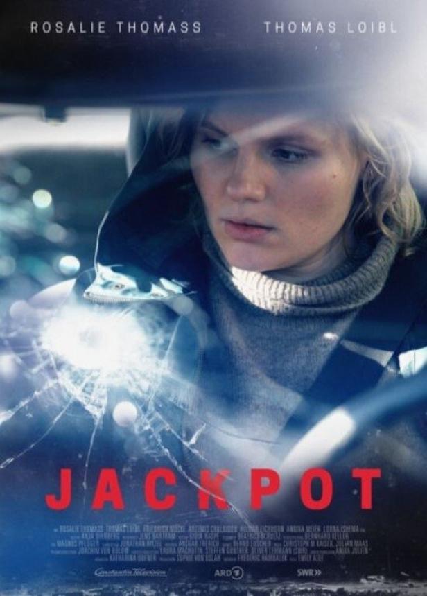 Das Filmplakat für „Jackpot“ zeigt Rosalie Thomass hinter einer zerbrochenen Windschutzscheibe.