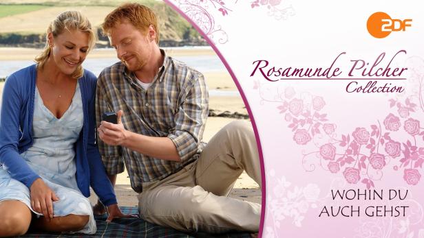 Ein Paar sitzt am Strand und schaut auf ein Smartphone.