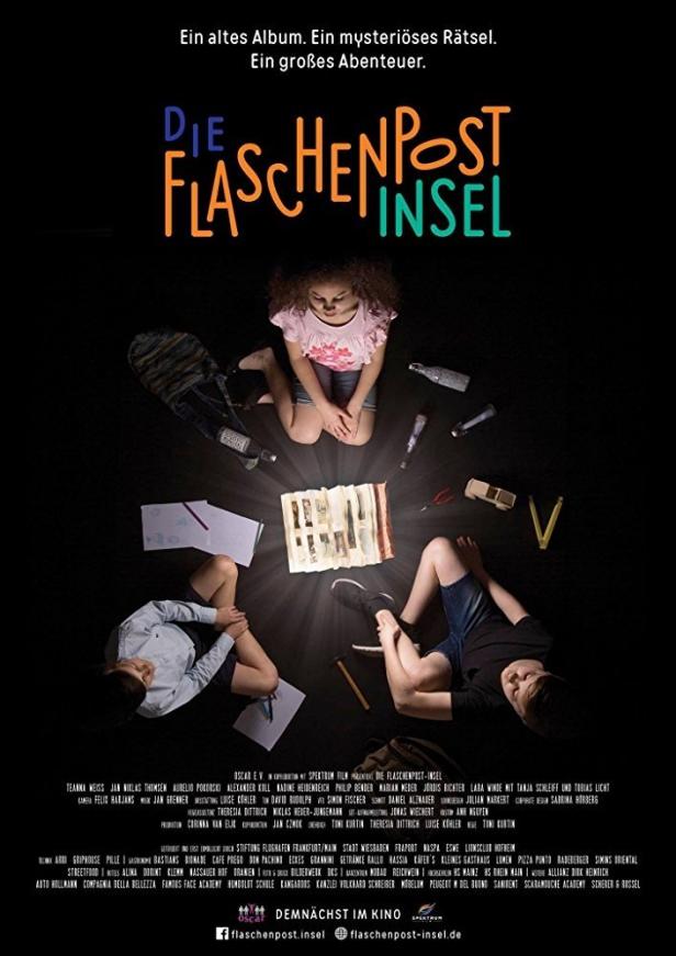 Das Filmplakat für „Die Flaschenpost-Insel“ zeigt drei Kinder, die um ein leuchtendes Fotoalbum sitzen.