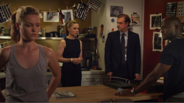 Vier Personen stehen in einer Küche und scheinen sich zu unterhalten.