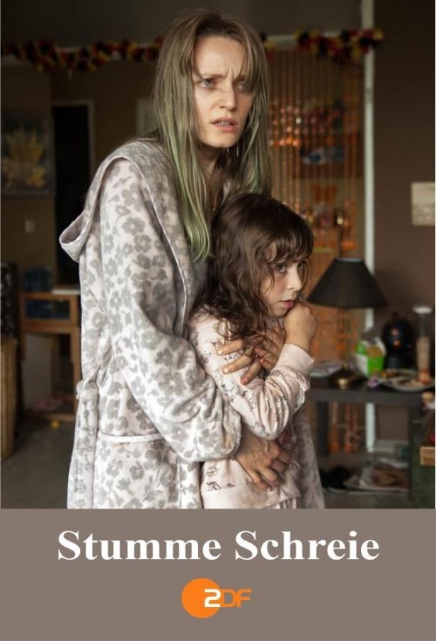 Eine besorgte Frau im Morgenmantel umarmt ein ängstliches kleines Mädchen.