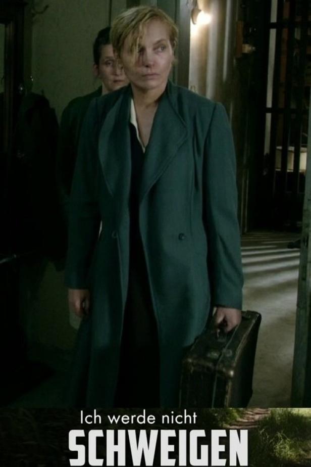 Eine Frau mit Mantel und Koffer, möglicherweise auf der Flucht.