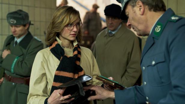 Eine Frau mit Brille zeigt einem Grenzbeamten ihren Pass.