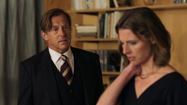 Ein Mann im Anzug schaut besorgt auf eine Frau mit dunklem Kleid.