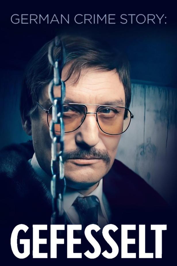 Das Filmplakat für „German Crime Story: Gefesselt“ zeigt einen Mann mit Brille hinter einer Kette.