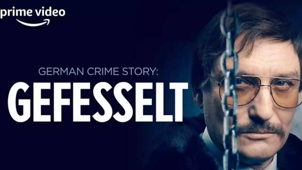 Das Filmplakat für „German Crime Story: Gefesselt“ auf Prime Video zeigt einen Mann mit Brille hinter einer Kette.