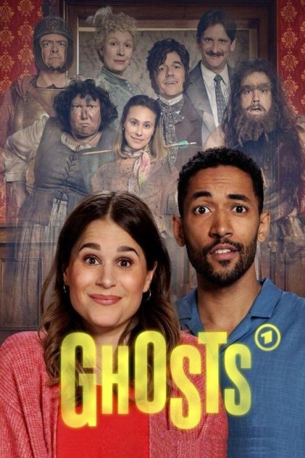 Das Filmplakat zur deutschen Fernsehserie „Ghosts“ zeigt ein junges Paar vor einer Gruppe von Geistern.