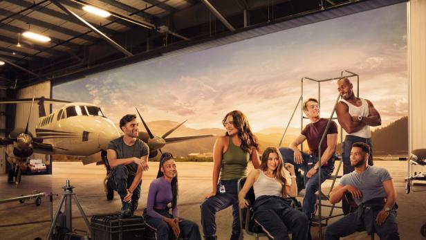 Die Besetzung der Fernsehserie „SkyMed“ posiert vor einem Flugzeug in einem Hangar.