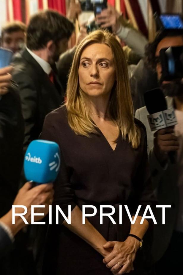 Eine Frau wird von Reportern umringt, im Vordergrund Mikrofone.