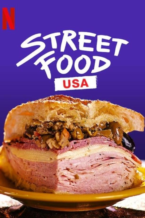 Ein riesiges Sandwich mit Wurst, Käse und Oliven auf einem Teller, im Stil der Netflix-Serie „Street Food USA“.