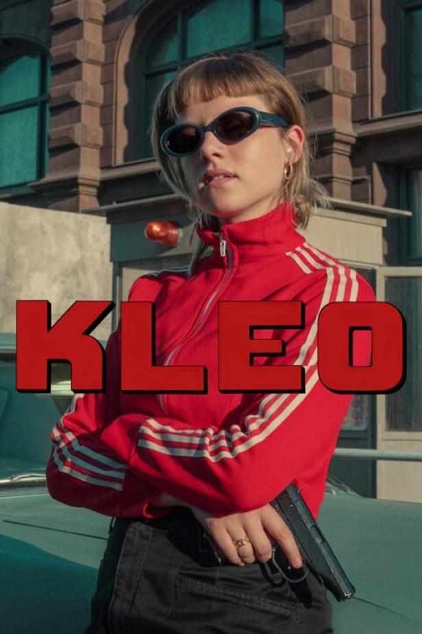 Eine Frau mit Sonnenbrille und roter Jacke hält eine Pistole; im Vordergrund der Schriftzug „Kleo“.