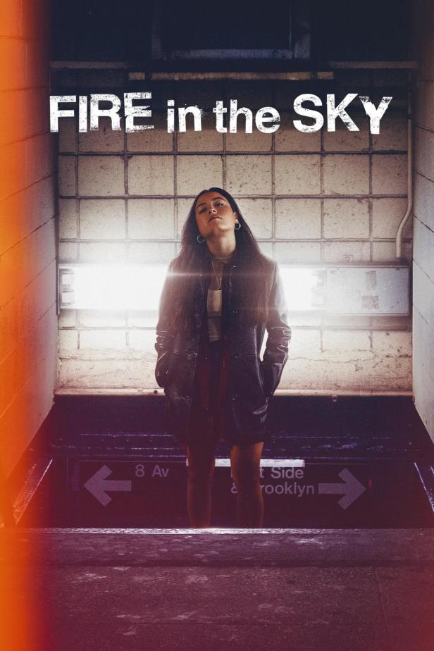 Eine Frau steht vor dem Eingang zu einer U-Bahn-Station mit dem Schriftzug „Fire in the Sky“.