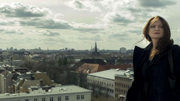 Eine Frau steht vor der Skyline von Berlin.