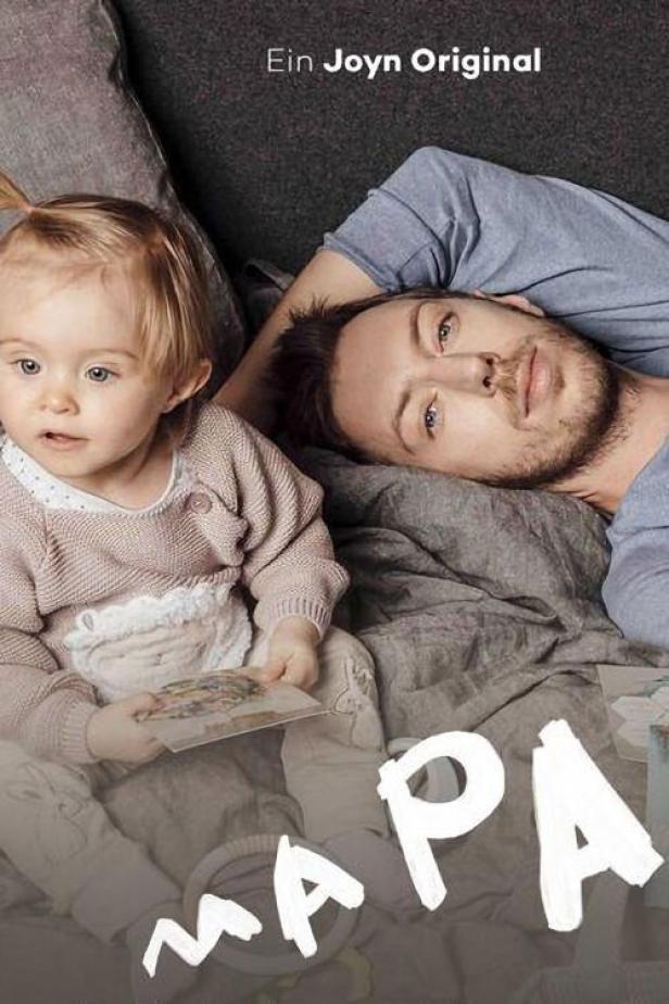 Ein Mann liegt mit einem kleinen Kind auf dem Bett.