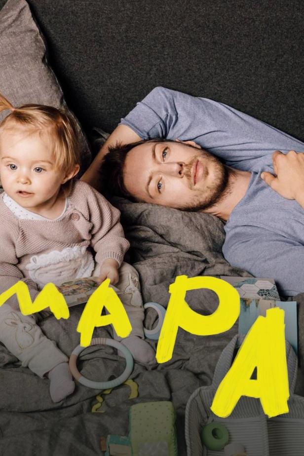 Ein Vater liegt mit seiner kleinen Tochter auf einer Decke.