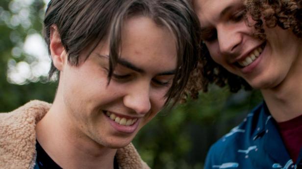 Zwei junge Männer lächeln einander an.