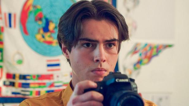 Ein junger Mann mit braunen Haaren fotografiert mit einer Canon-Kamera.