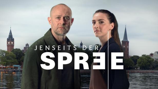 Ein Mann und eine Frau vor der Kulisse der Spree und historischer Gebäude in Berlin für „Jenseits der Spree“.