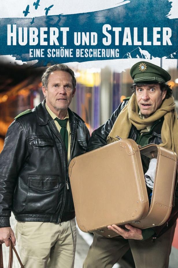 Das Filmplakat zu „Hubert und Staller: Eine schöne Bescherung“ zeigt die beiden Hauptdarsteller mit einem Koffer.