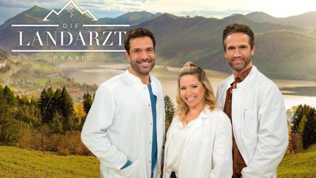 Drei lächelnde Ärzte vor einer malerischen Bergkulisse für „Der Landarzt“.