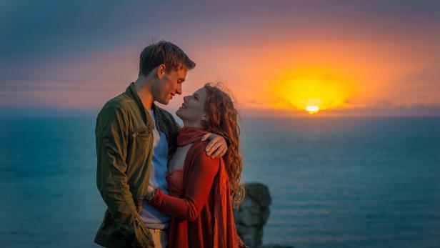 Ein Paar umarmt sich vor einem Sonnenuntergang am Meer.