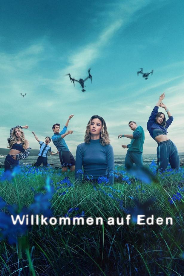 Eine Gruppe junger Leute steht auf einer Wiese unter Drohnen am Himmel.