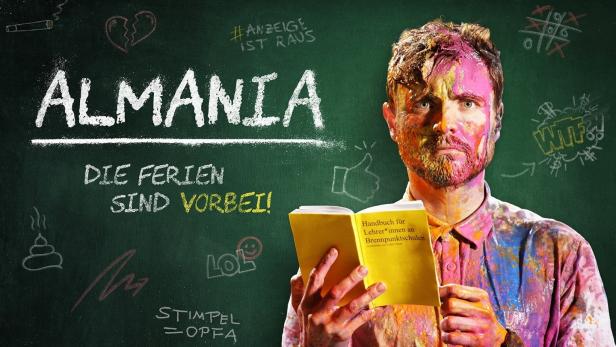 Ein mit Farbe beschmierter Mann liest vor einer Tafel mit der Aufschrift „Almania: Die Ferien sind vorbei!“.
