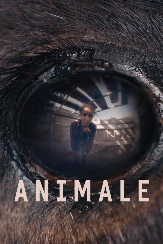Das Auge eines Tieres spiegelt eine junge Frau in einem schuppenartigen Raum wider; Filmposter „Animale“.