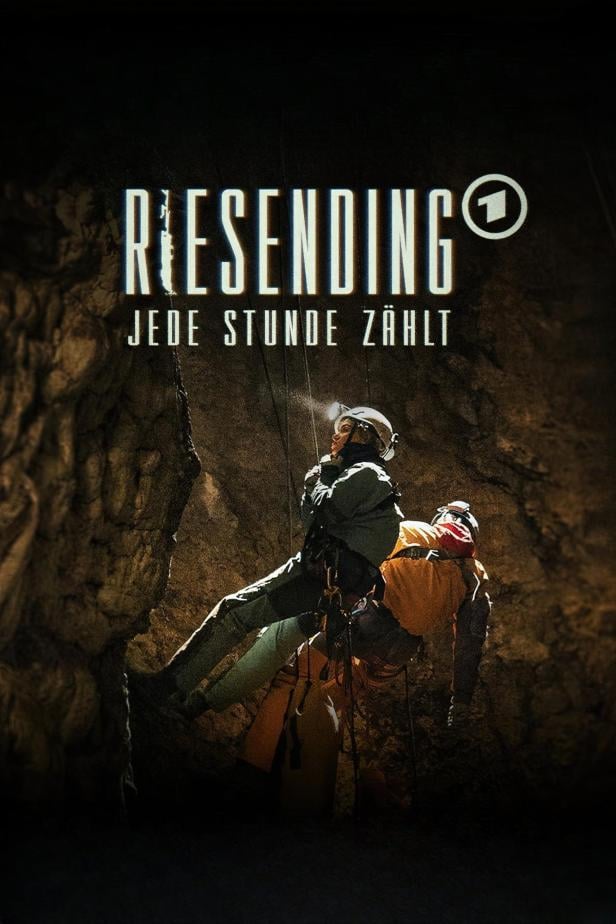 Ein Höhlenforscher seilt sich mit einer verletzten Person in einer dunklen Höhle ab.