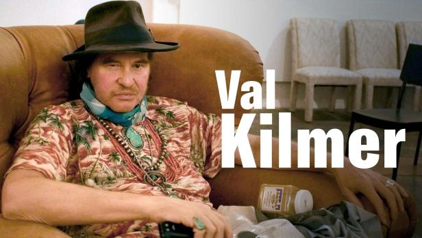 Val Kilmer sitzt in einem Sessel mit Hut und Hawaiihemd.