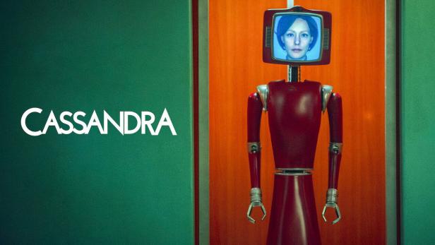 Ein roter Roboter mit einem Bildschirm, der das Gesicht einer Frau zeigt, neben dem Schriftzug „Cassandra“.