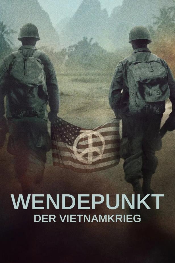 Zwei Soldaten tragen eine amerikanische Flagge mit einem Friedenssymbol vor einer Bergkulisse.