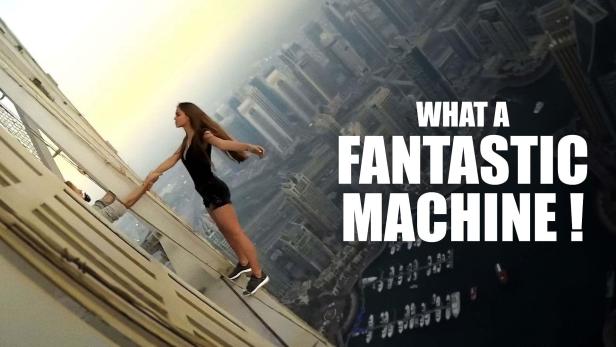 Eine Frau hängt an der Seite eines Wolkenkratzers und hält die Hand einer anderen Person.