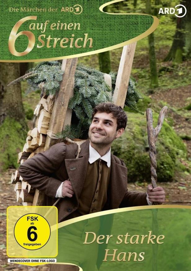 Ein Mann im Wald, der Holz und einen kleinen Baum trägt, DVD-Cover von „Der starke Hans“.