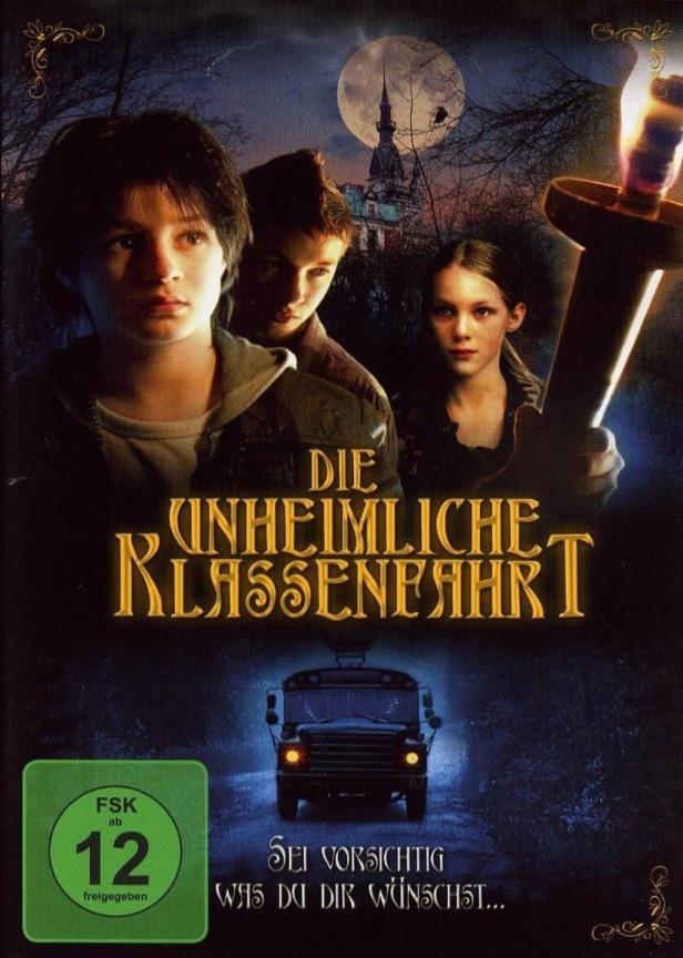Das Filmplakat für „Die unheimliche Klassenfahrt“ zeigt drei Kinder vor einem gruseligen Schloss und einem Schulbus.