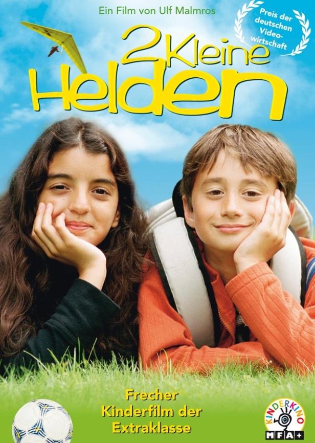 Das Filmplakat für „2 Kleine Helden“ zeigt zwei Kinder im Gras liegend.