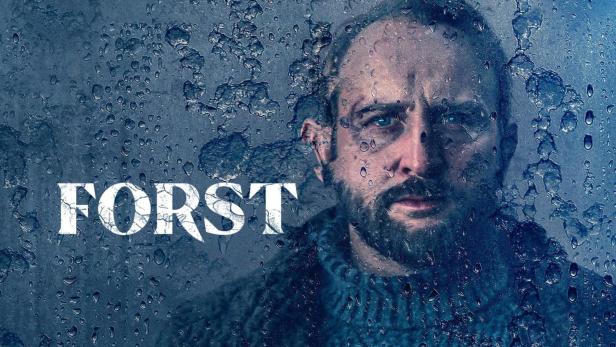 Ein Porträt des Schauspielers Ksawery Szlenkier als Kommissar Forst vor einem regnerischen Hintergrund.