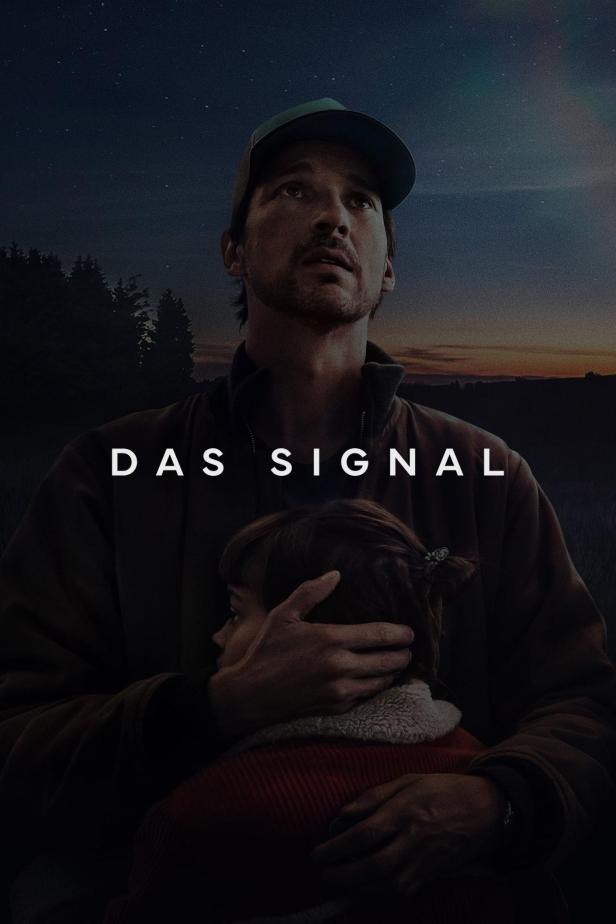Ein Mann umarmt ein Kind vor dem Hintergrund des Posters für „Das Signal“.