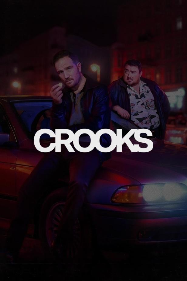 Zwei Männer posieren vor einem Auto für die Serie „Crooks“.